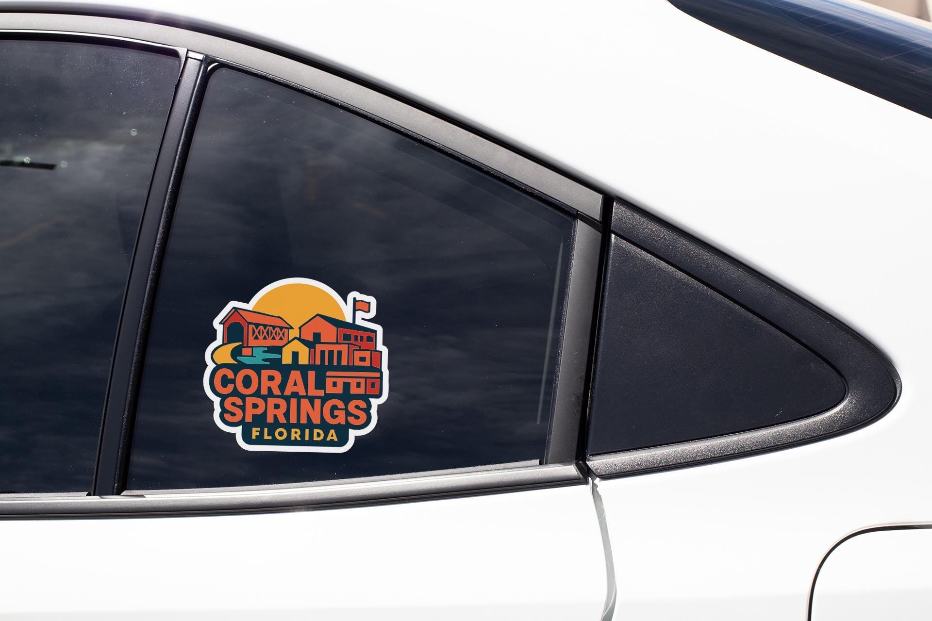 A sticker on the side of a car window, featuring a colorful illustration of a building and the text "Coral Springs, Florida".