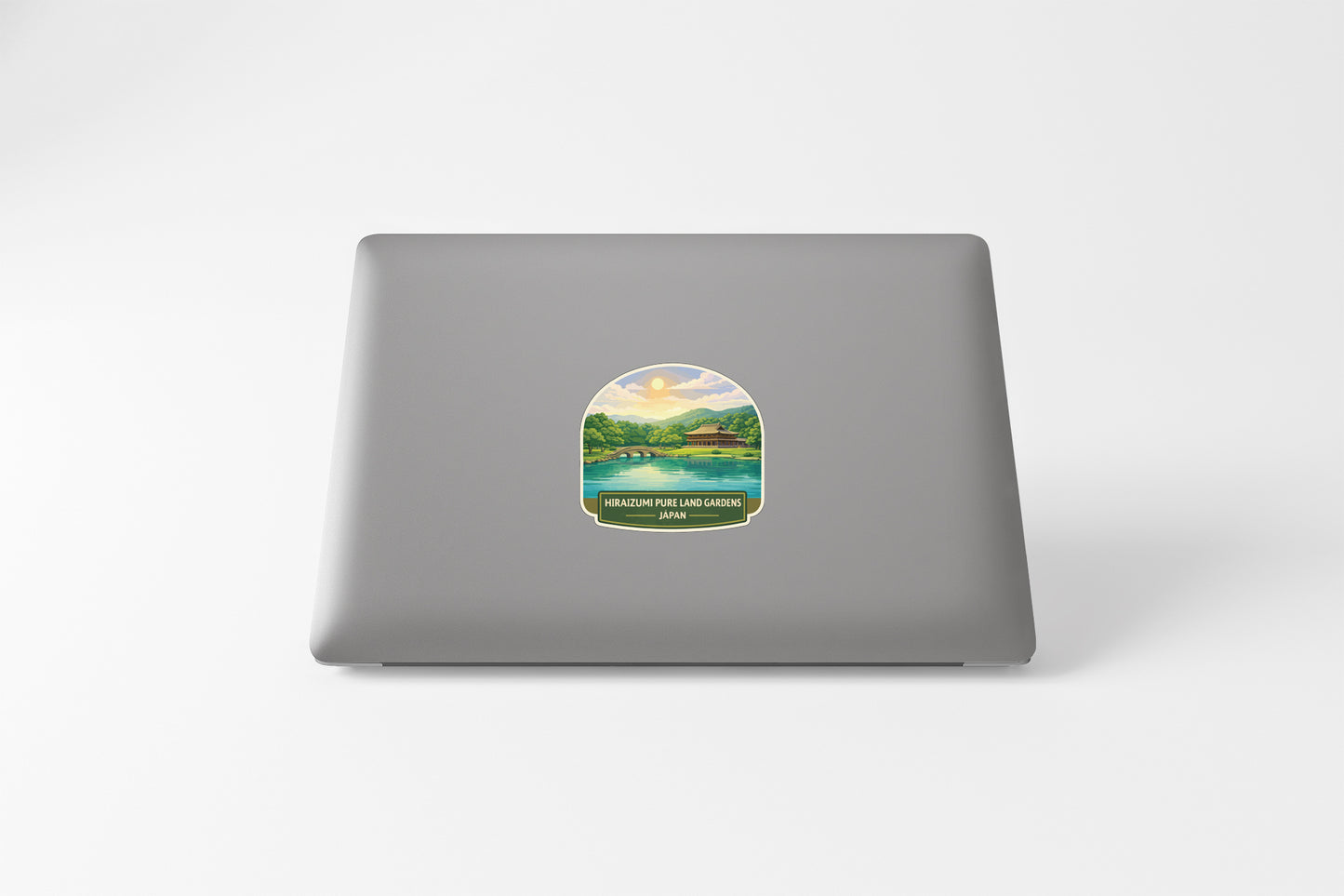 A sticker depicting a scenic landscape with a lake and mountains, placed on the back of a laptop computer.