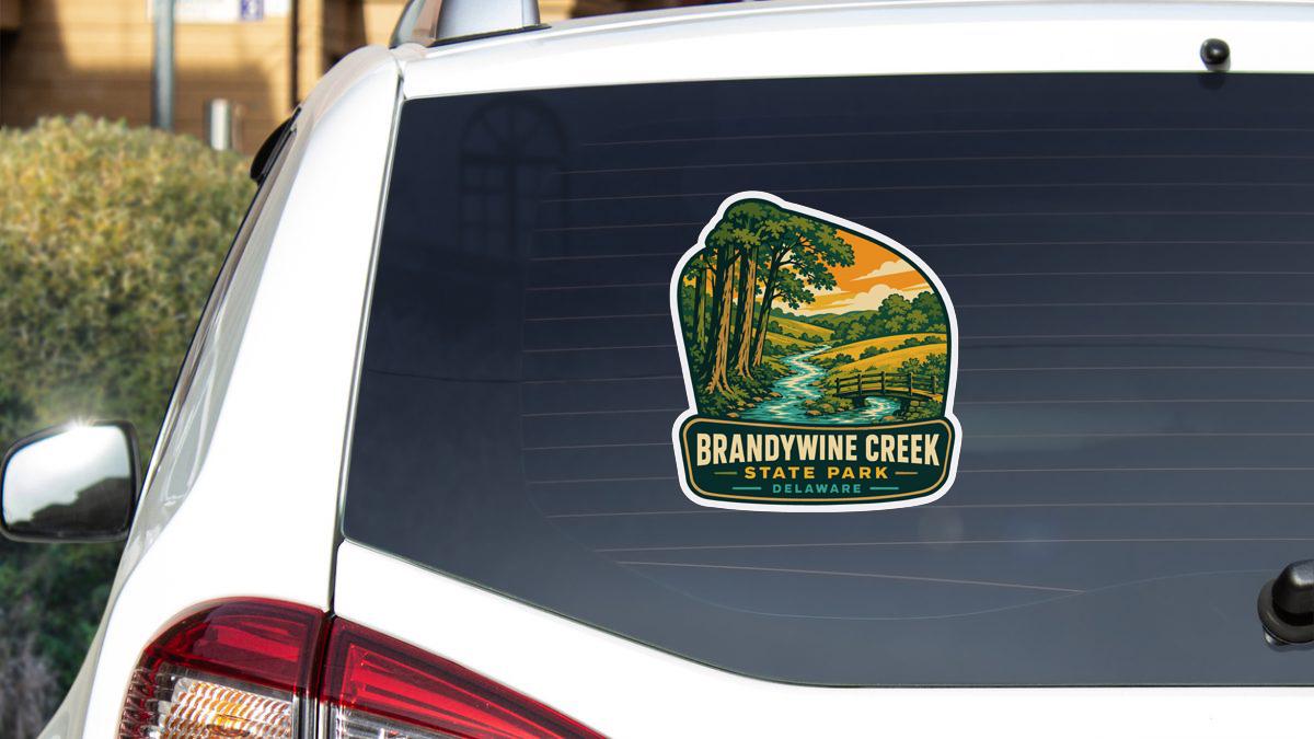 A sticker on the rear window of a white vehicle, depicting a scenic landscape with a river and trees.