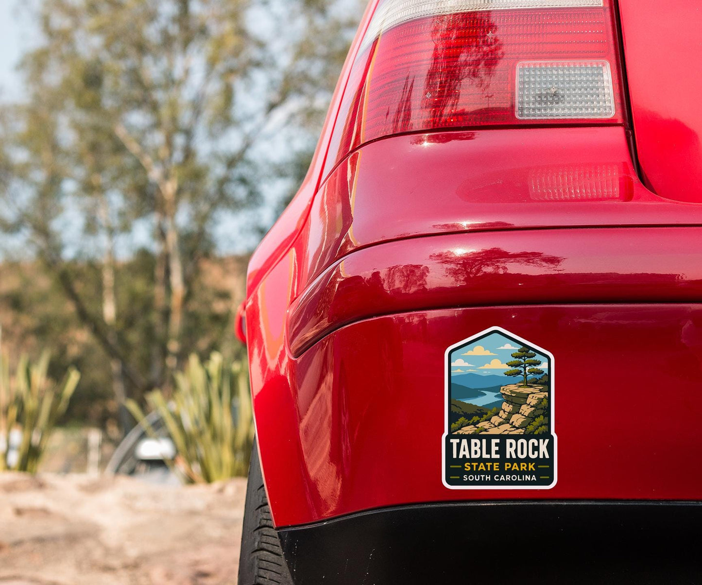 the rear end of a red car with a sticker on the trunk that says "Table Rock State Park South Carolina".
