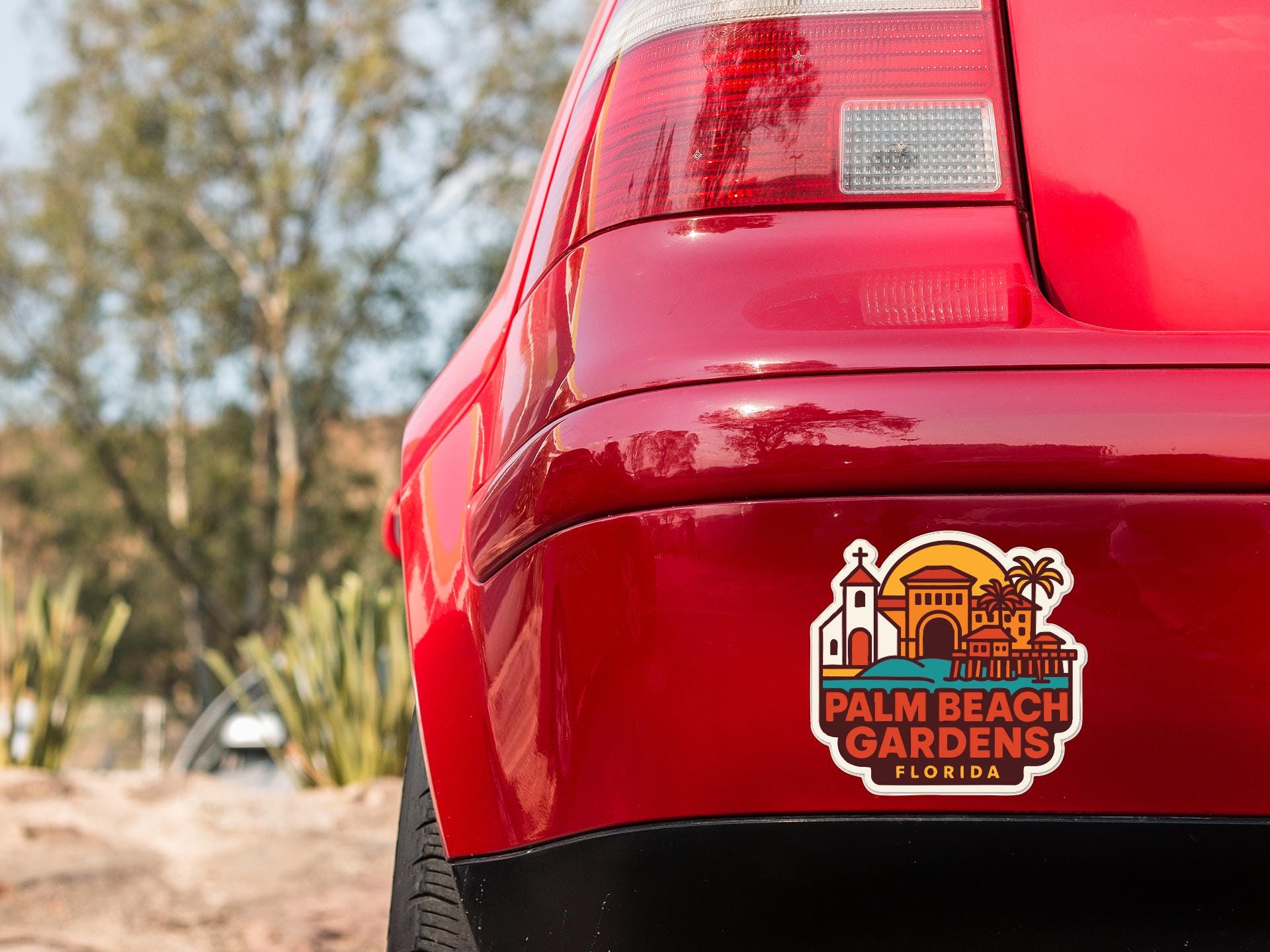 the rear end of a red car with a sticker on the trunk that says "Palm Beach Gardens Florida".