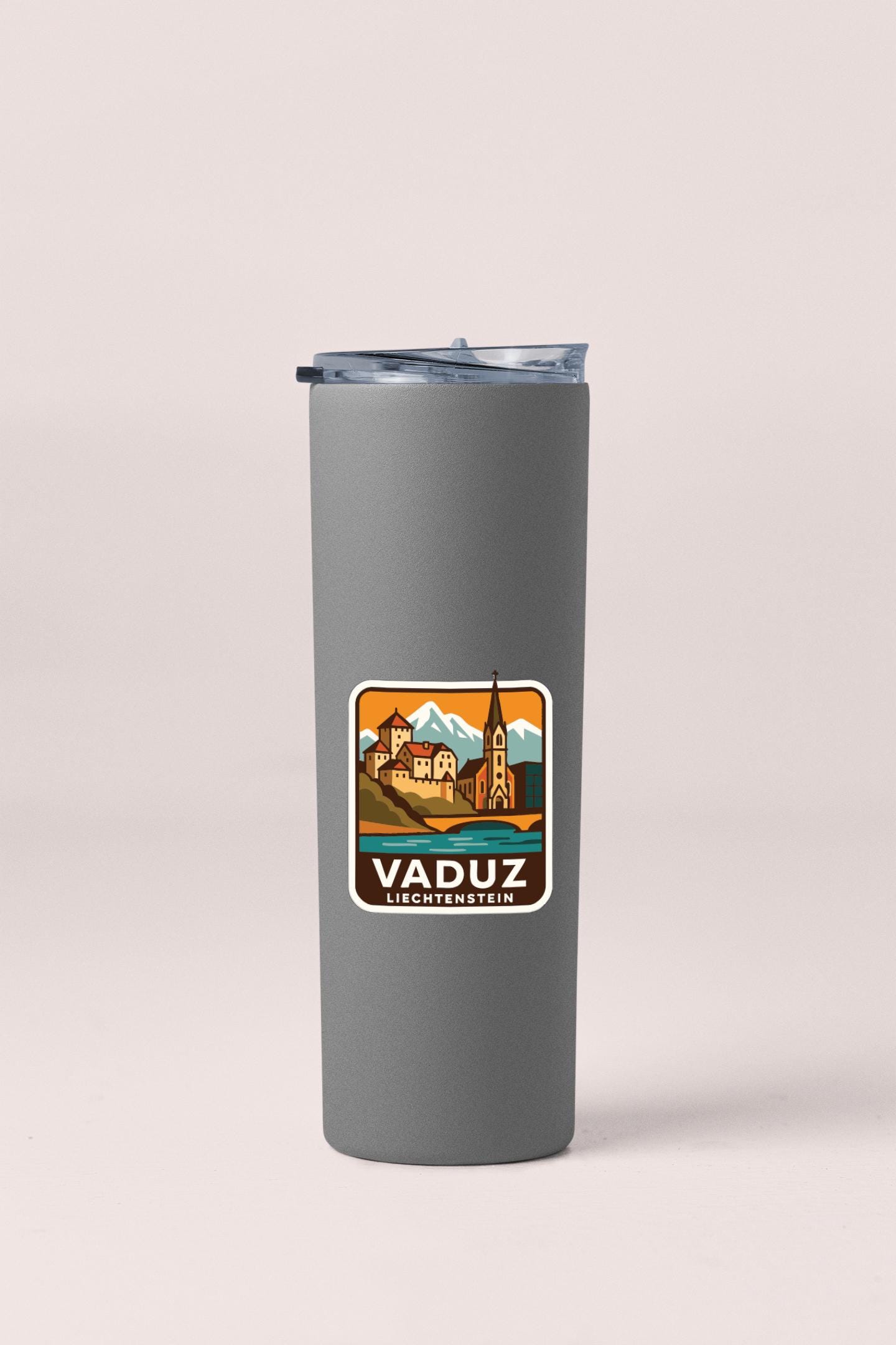 A gray insulated tumbler with a sticker depicting a scenic landscape and the text "VADUZ LIECHTENSTEIN".