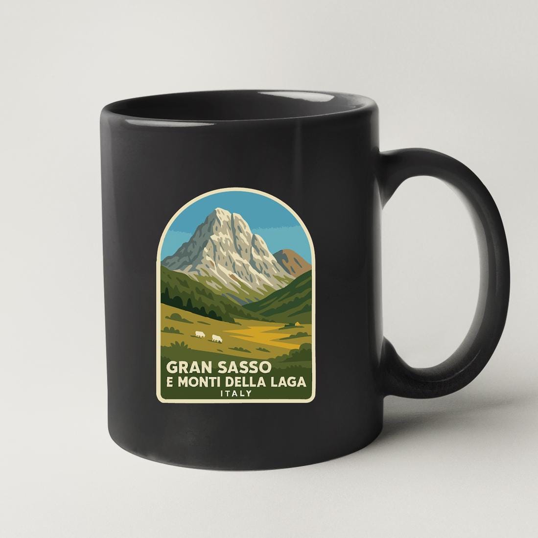 A black coffee mug with a graphic design depicting a mountain landscape.