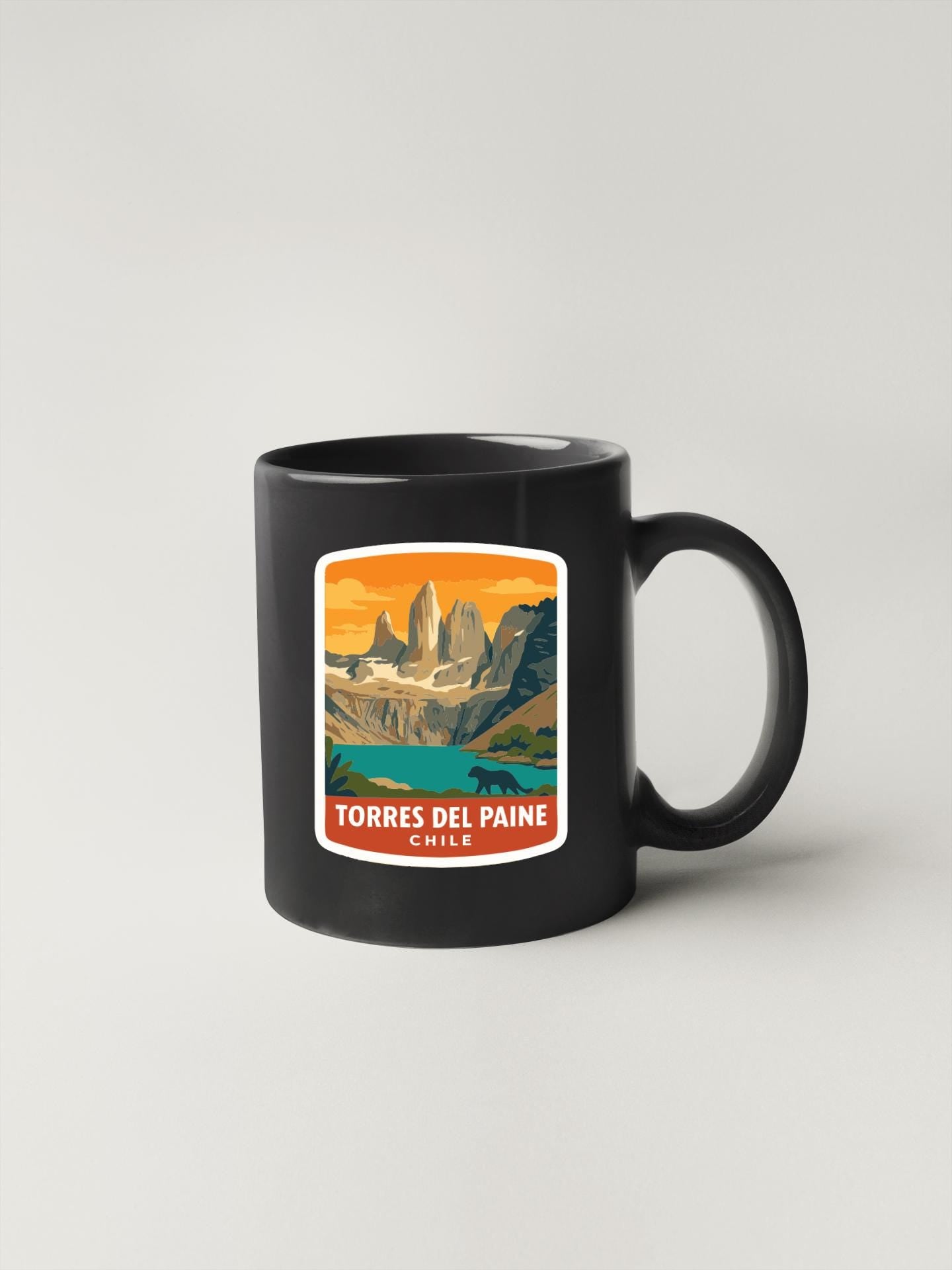 A black coffee mug with a sticker depicting a scenic mountain landscape.