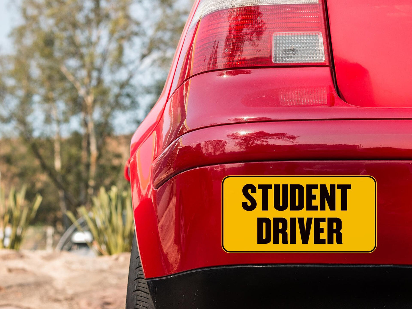 a red car with a yellow student driver sign on it