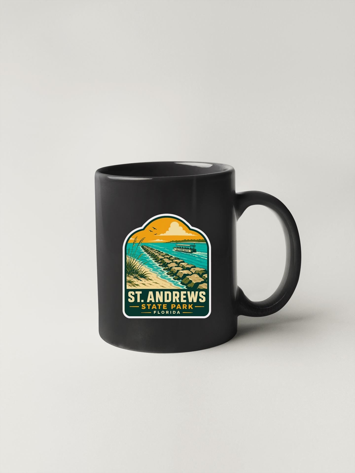 A black coffee mug with a graphic design depicting St Andrews State Park in Florida.