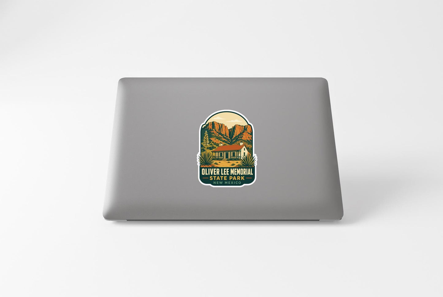 A sticker on the back of a laptop, depicting a scenic landscape with mountains and a building.