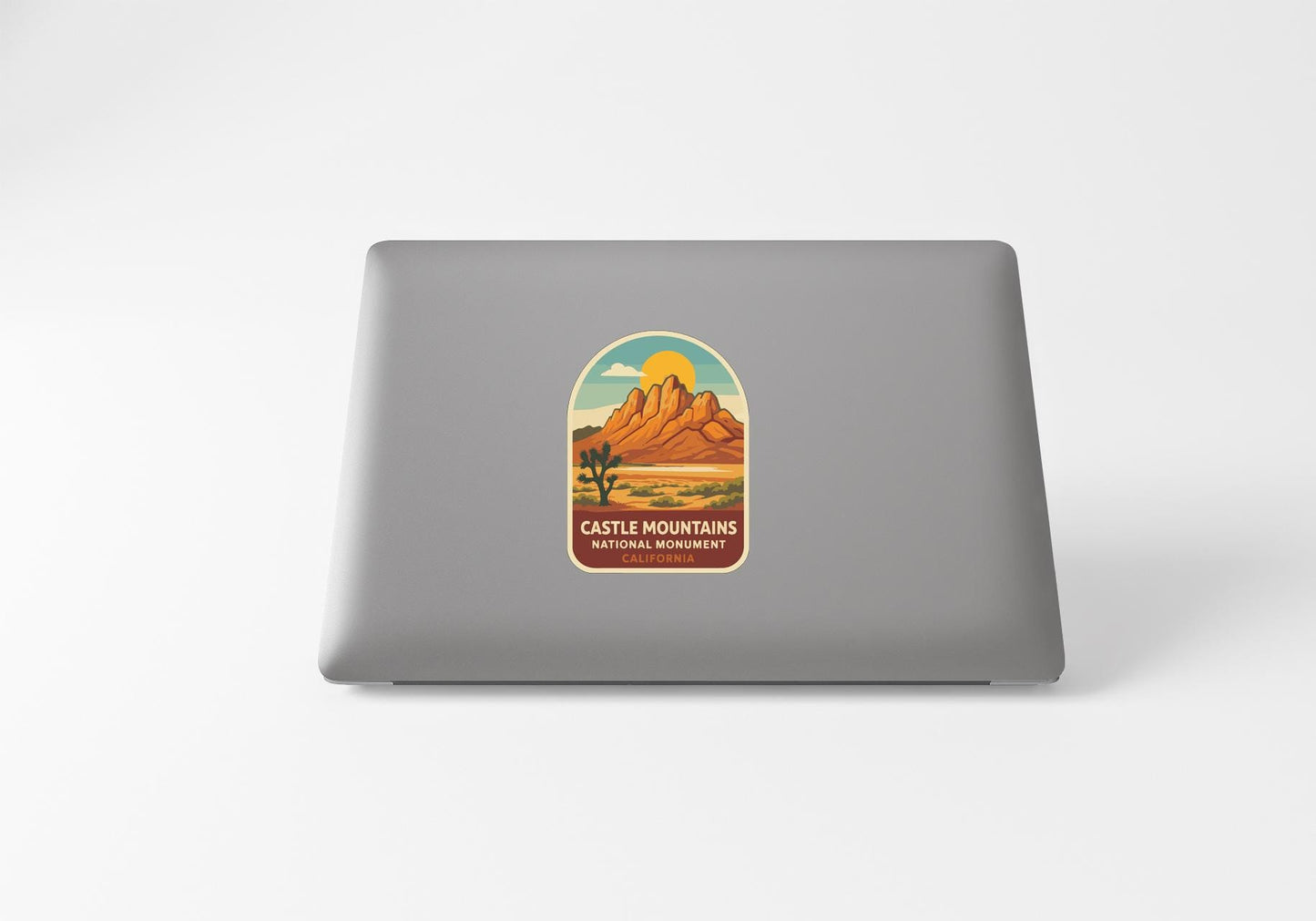 a sticker with a desert landscape and mountains on the back of a laptop.