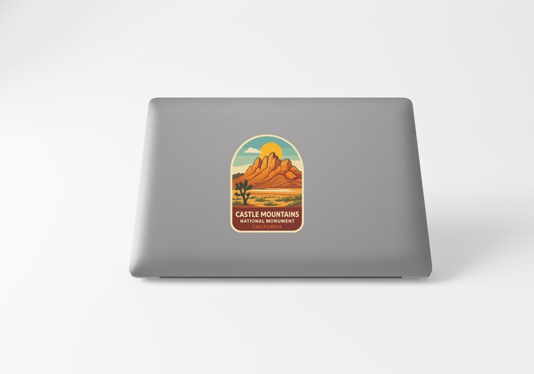 a sticker with a desert landscape and mountains on the back of a laptop.
