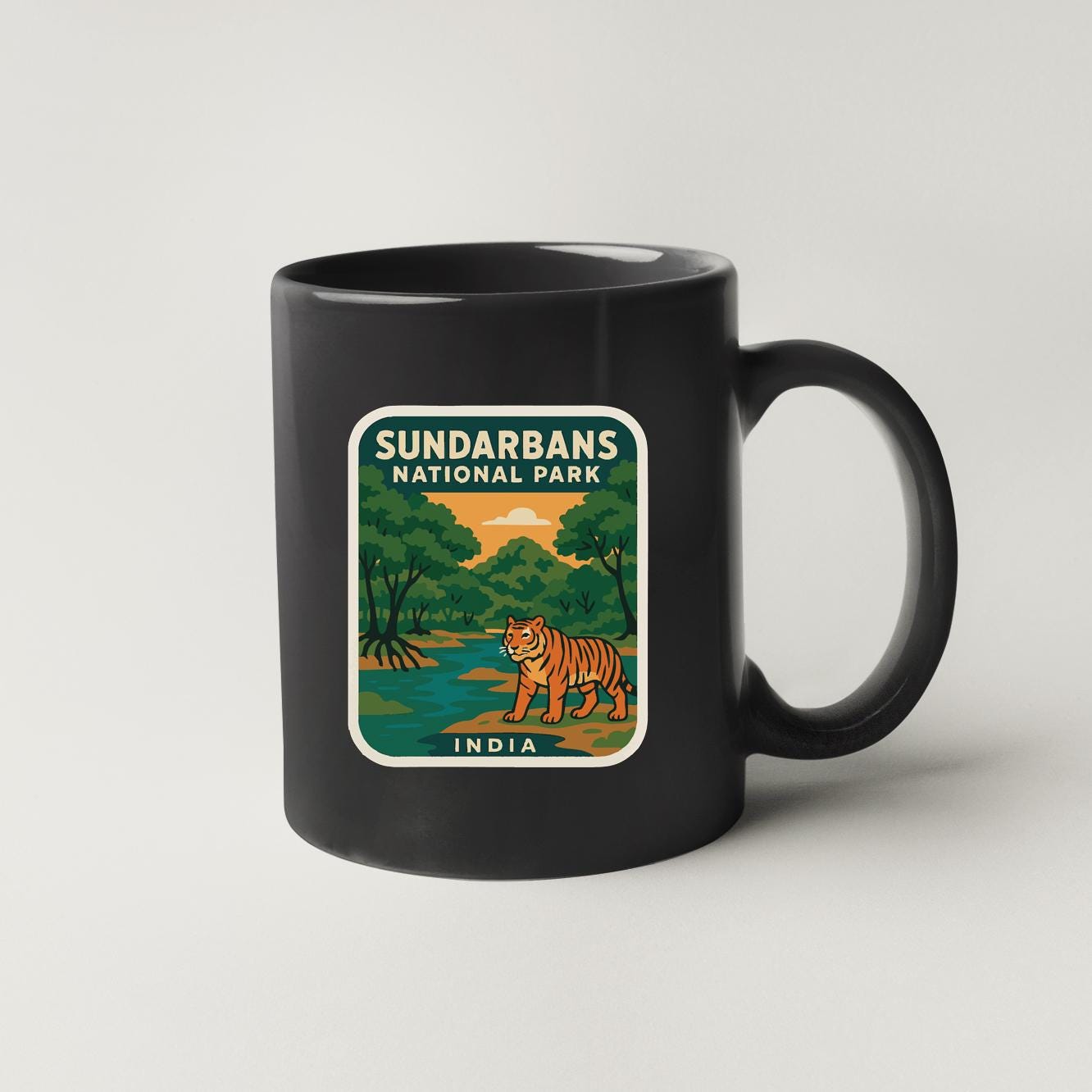 A black coffee mug with a graphic design depicting a tiger in a natural setting, surrounded by trees and a body of water.
