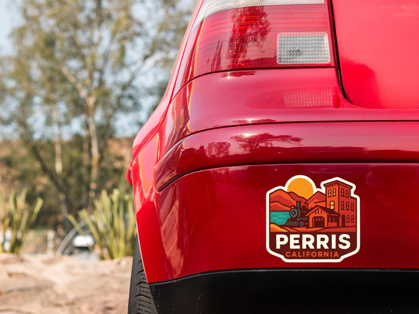 the rear end of a red car with a sticker on the back window that says "PERRIS CALIFORNIA".
