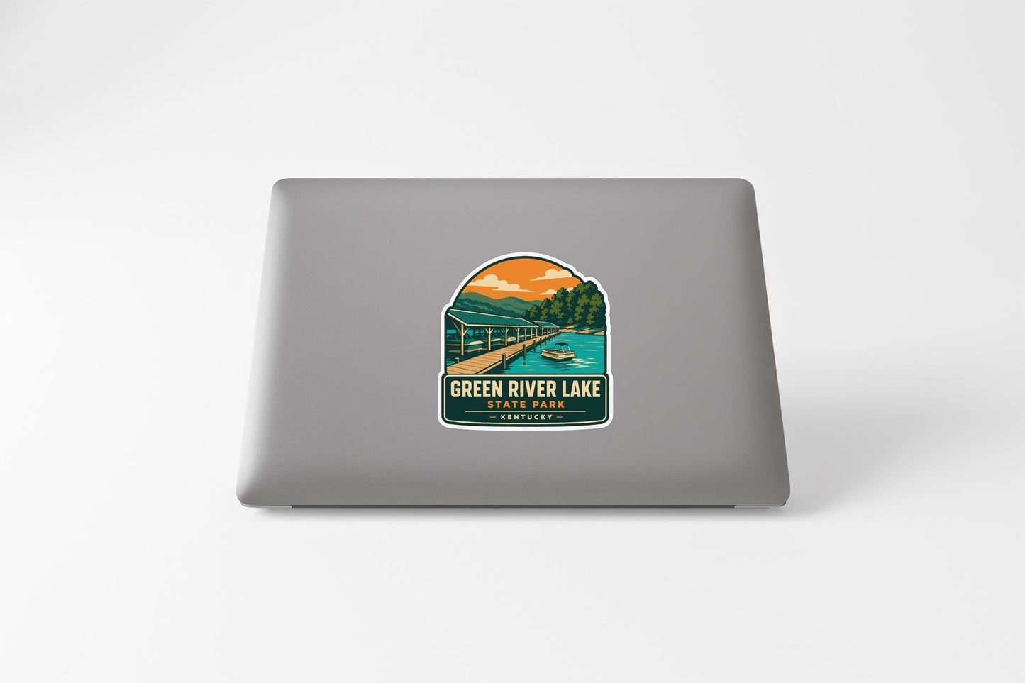 A sticker on the back of a laptop, depicting a scenic landscape with a bridge, trees, and a body of water.
