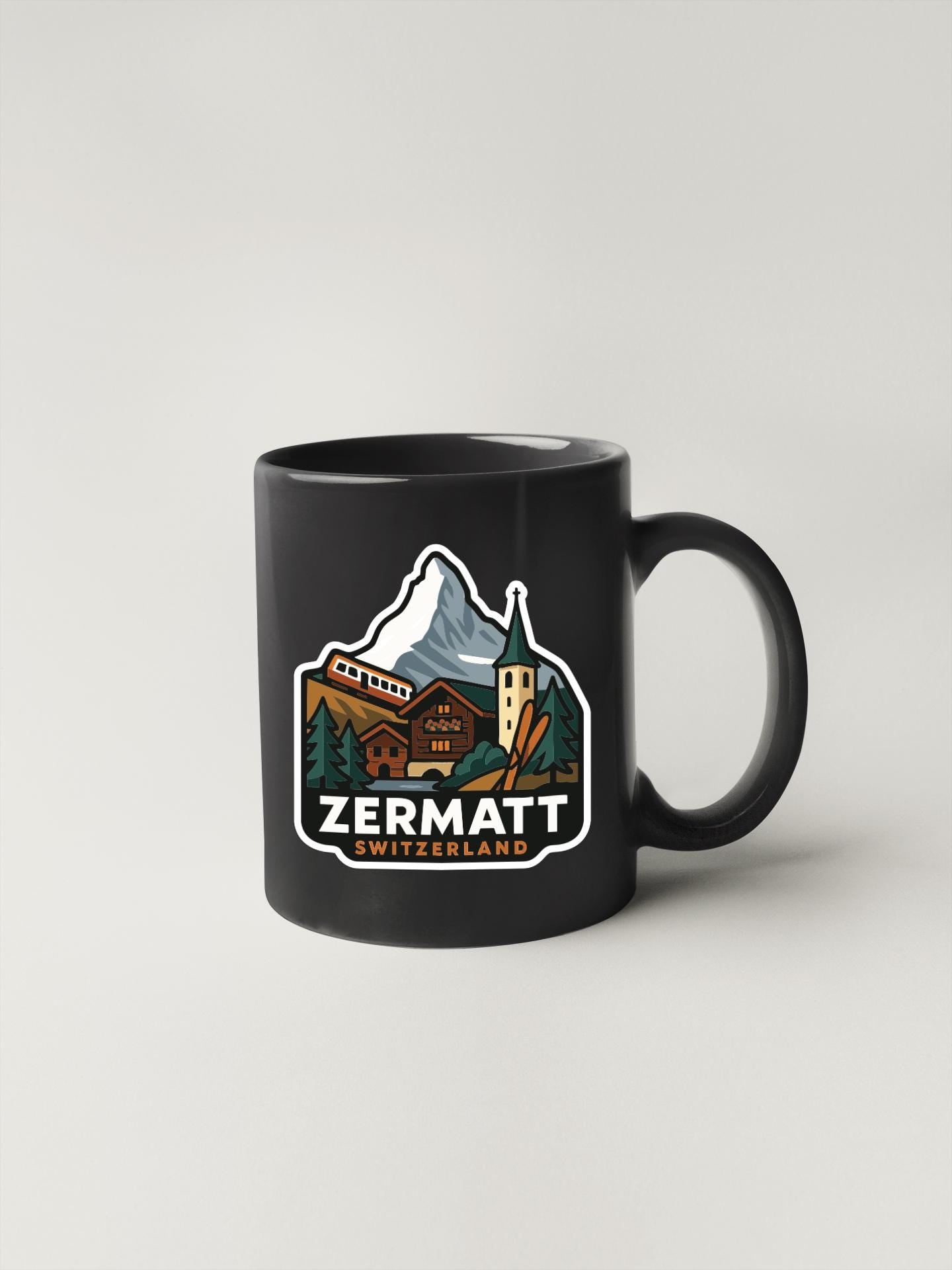 A black coffee mug with a colorful illustration of a mountain landscape and a Swiss mountain on it, along with the text "ZERMATT SWITZERLAND".