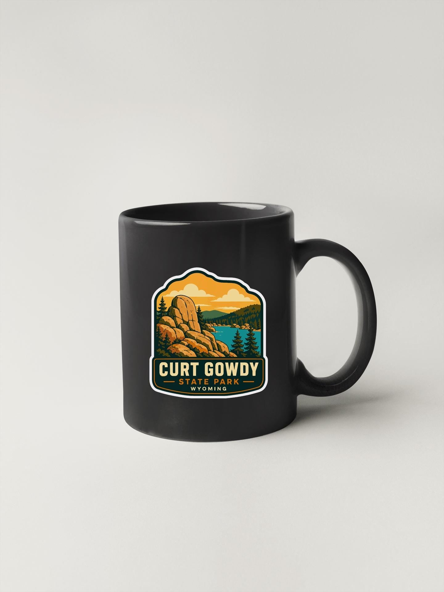 A black coffee mug with a graphic design featuring a mountain landscape and the text "Curt Gowdy State Park, Wyoming".