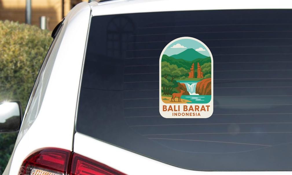 A sticker on the rear window of a car, depicting a scenic landscape with mountains, a waterfall, and a temple.
