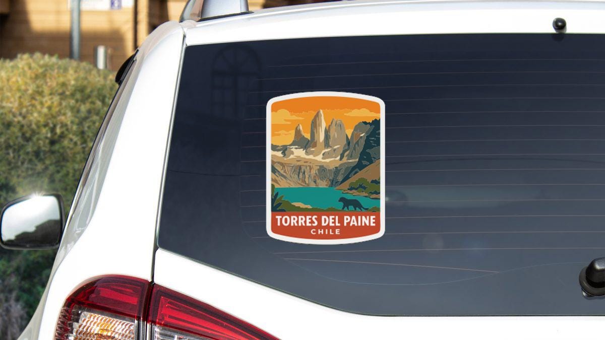 A sticker on the rear window of a car, depicting a scenic mountain landscape with a lake and a waterfall.