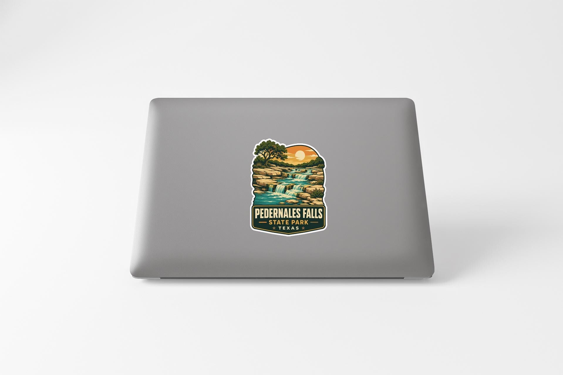 A sticker depicting a scenic landscape with a waterfall and a sunset, with the text "Pedernales Falls, Texas" printed on it.