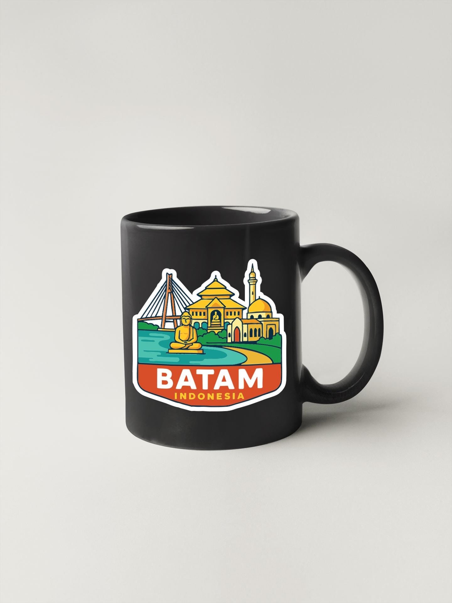 A black coffee mug with a colorful sticker depicting the city of Batam, Indonesia.