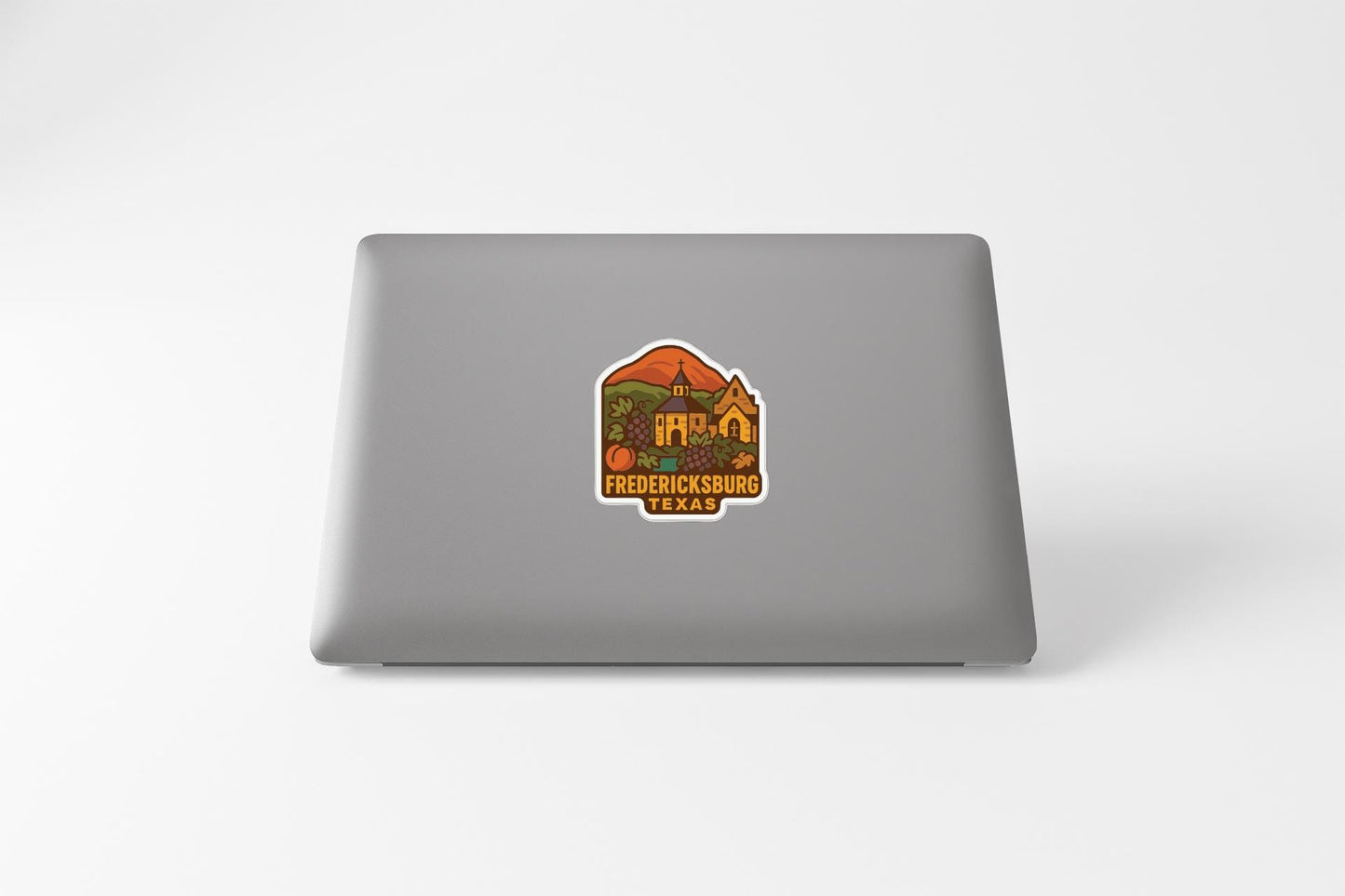 A sticker on the back of a laptop, depicting a scenic view of Fredericksburg, Texas.