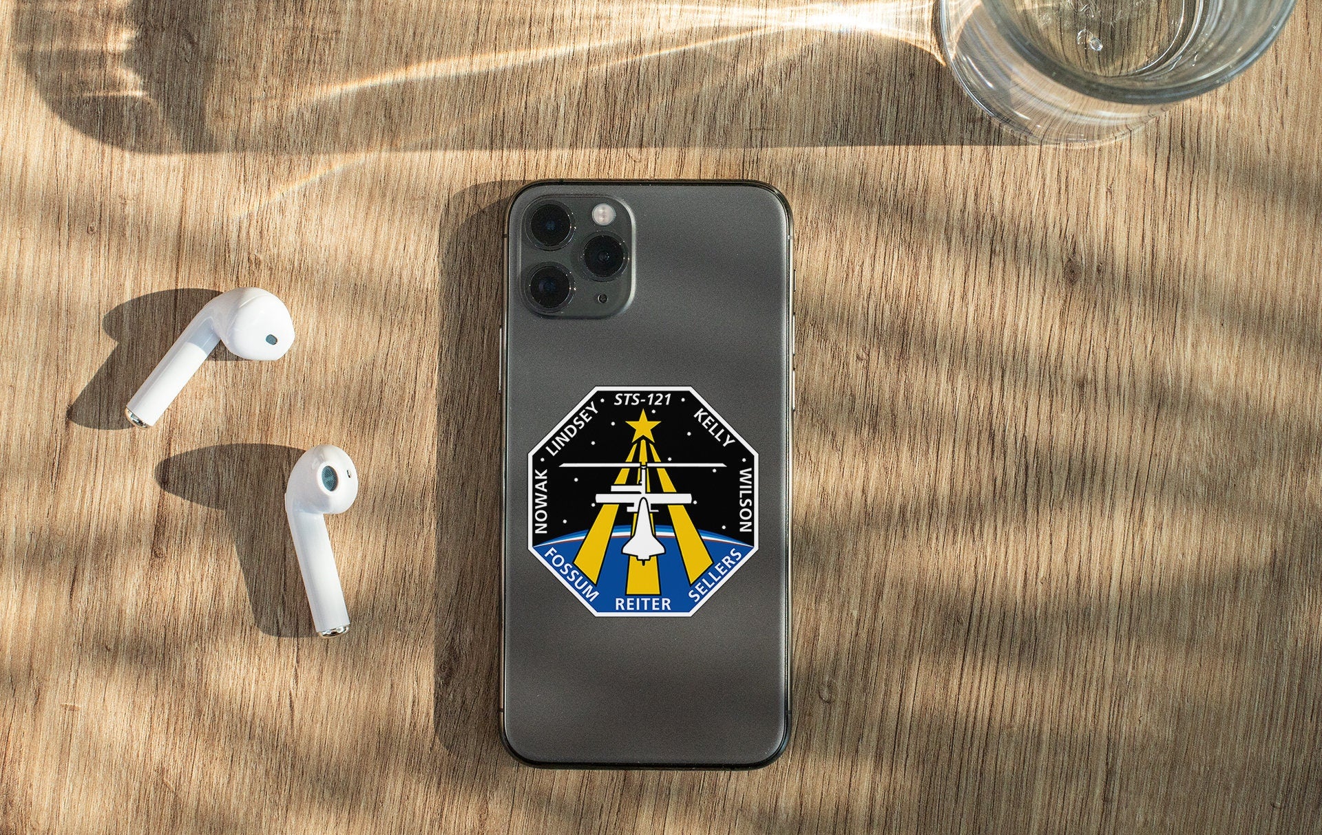 a phone with a sticker on it next to ear buds
