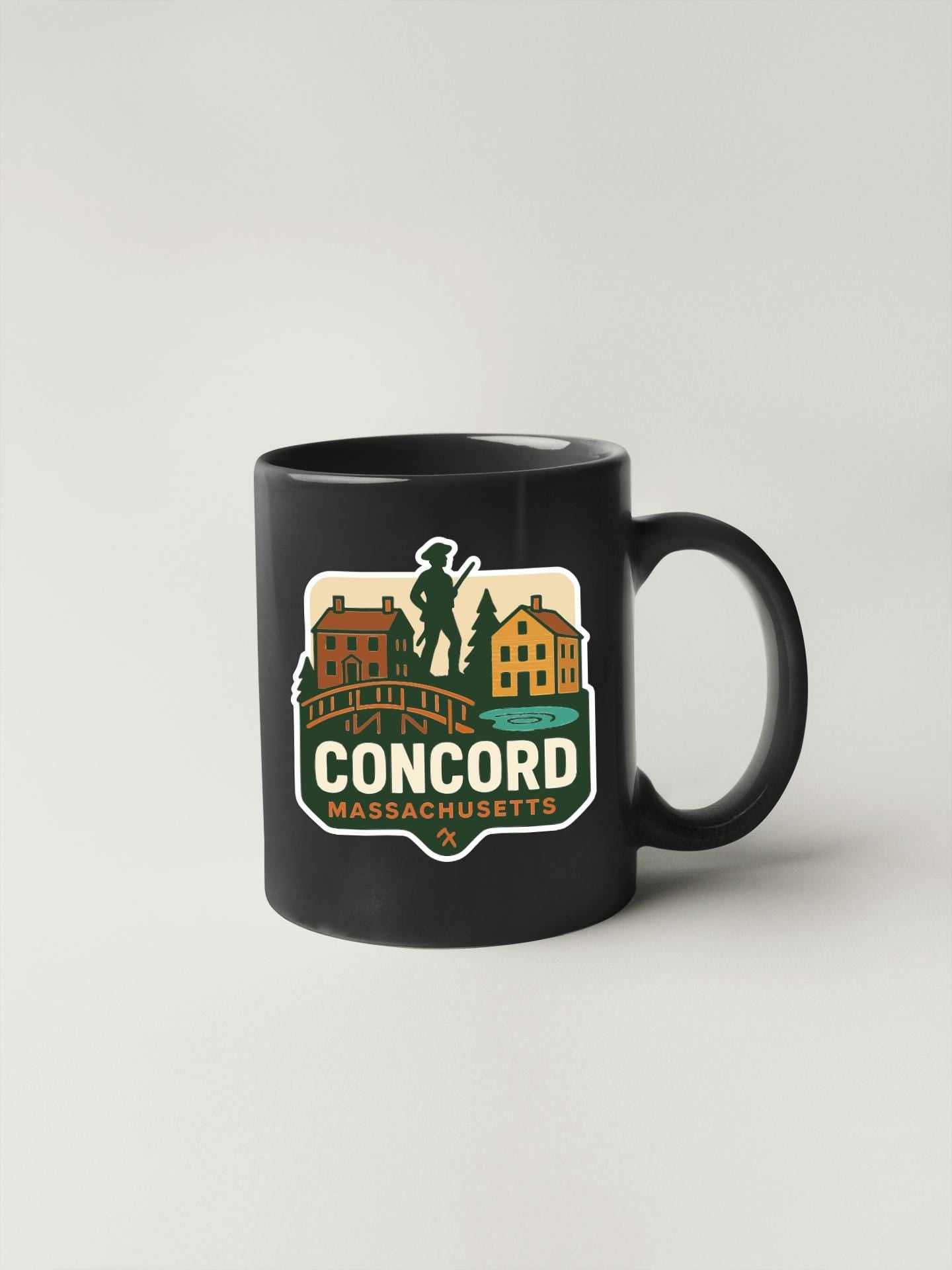A black coffee mug with a graphic design featuring a town scene and the text "Concord, Massachusetts".