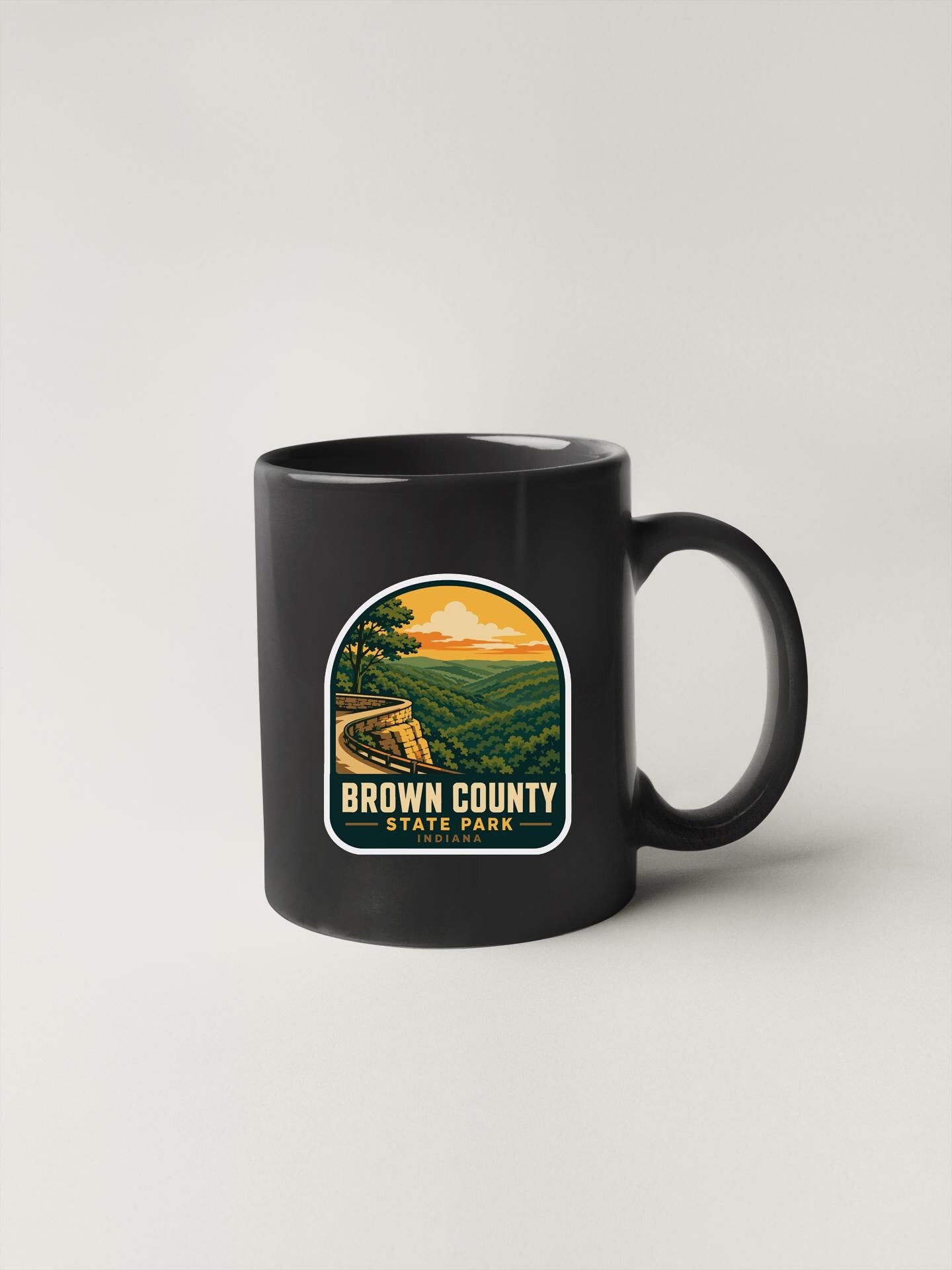 A black coffee mug with a label that says "Brown County State Park" and features an illustration of a scenic landscape.