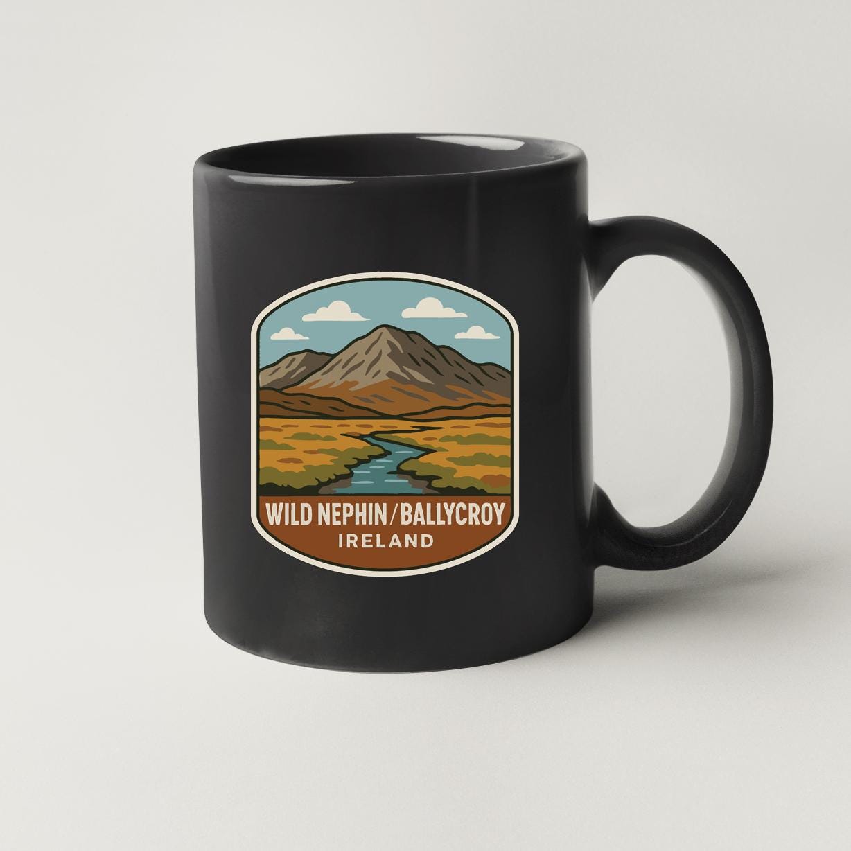 A black coffee mug with a graphic design depicting a mountain landscape and a river.