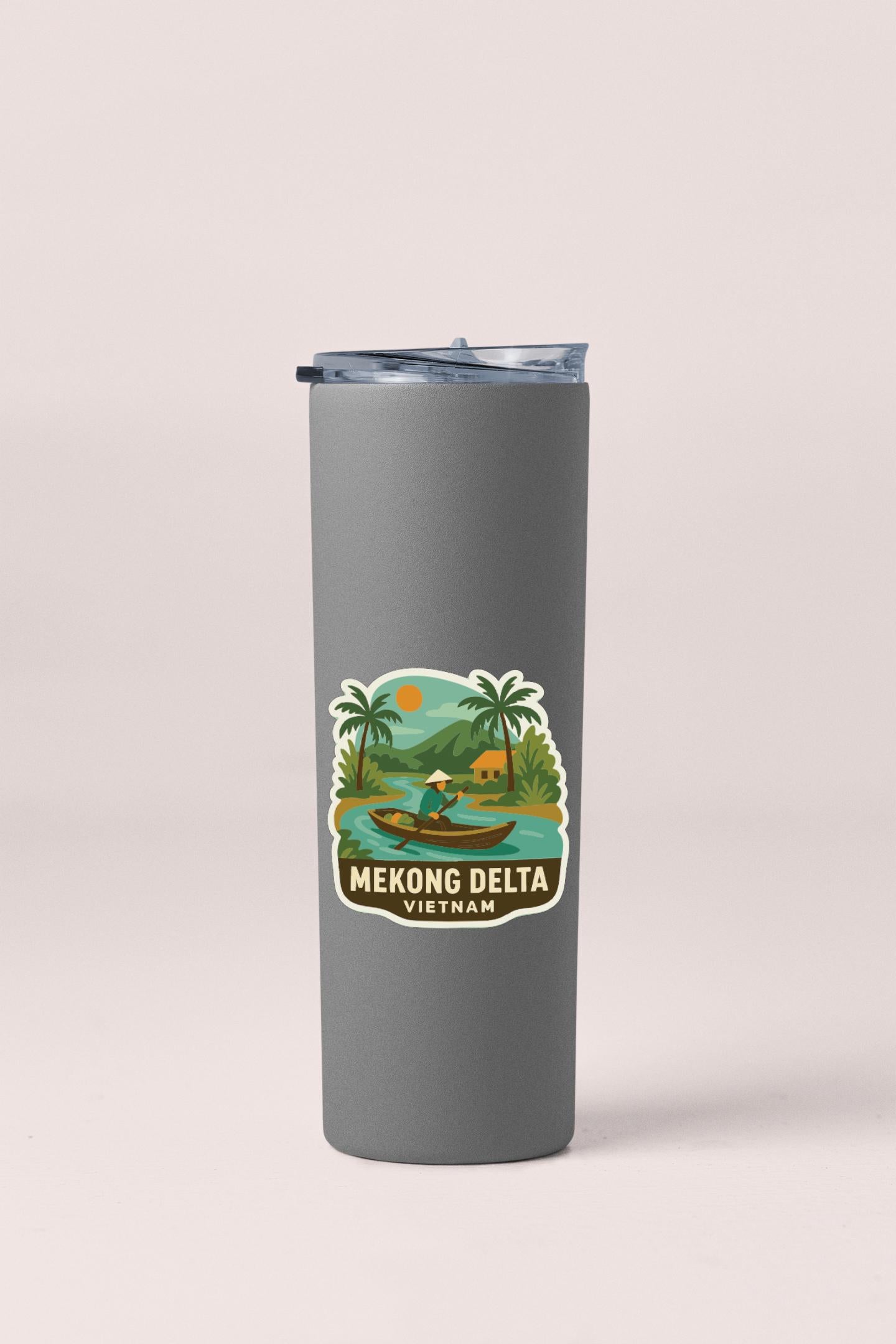A gray insulated tumbler with a sticker depicting a tropical landscape and a person in a boat.