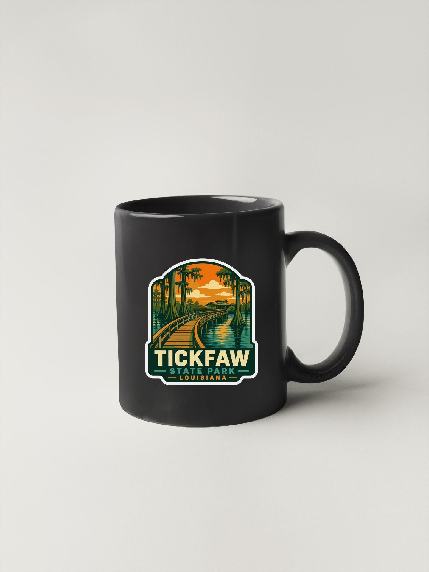 A black coffee mug with a colorful graphic design depicting a scenic landscape with a path, palm trees, and a sunset.