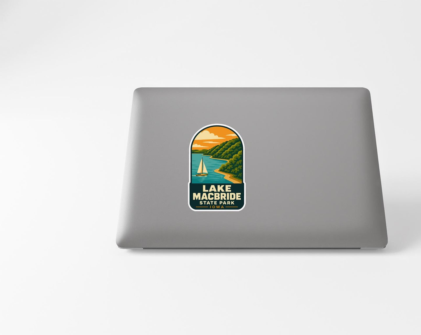 A sticker on the back of a laptop that features a scenic landscape with a lake, mountains, and a sailboat.