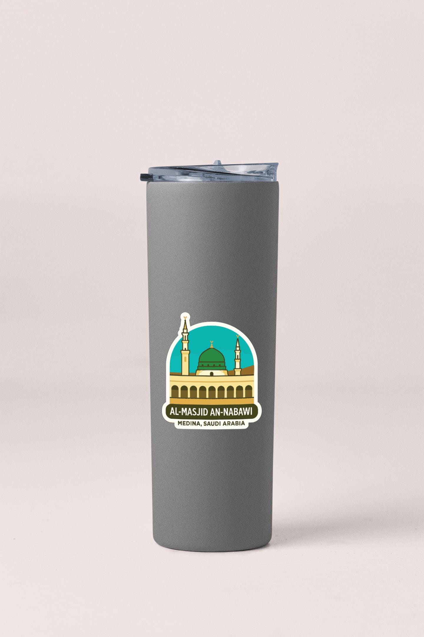 A gray tumbler with a sticker depicting the Al-Majid Al-Nabawi, a famous mosque located in Medina, Saudi Arabia.