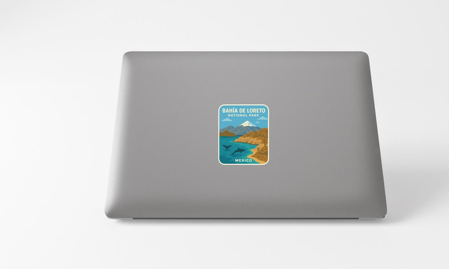 A sticker on the back of a laptop, depicting a scenic landscape with mountains, water, and a blue sky.