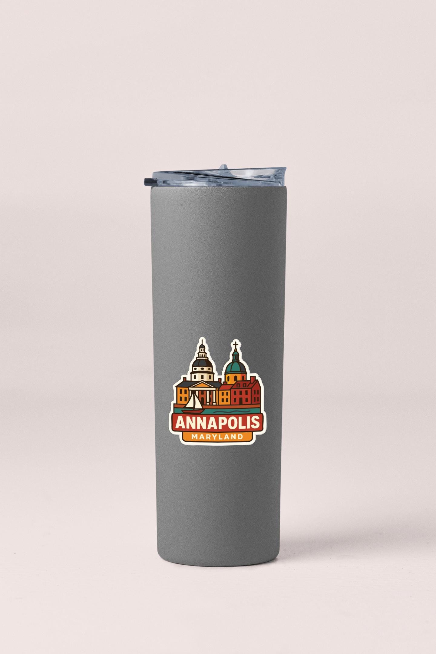 A gray insulated tumbler with a printed sticker depicting the Annapolis, Maryland skyline.