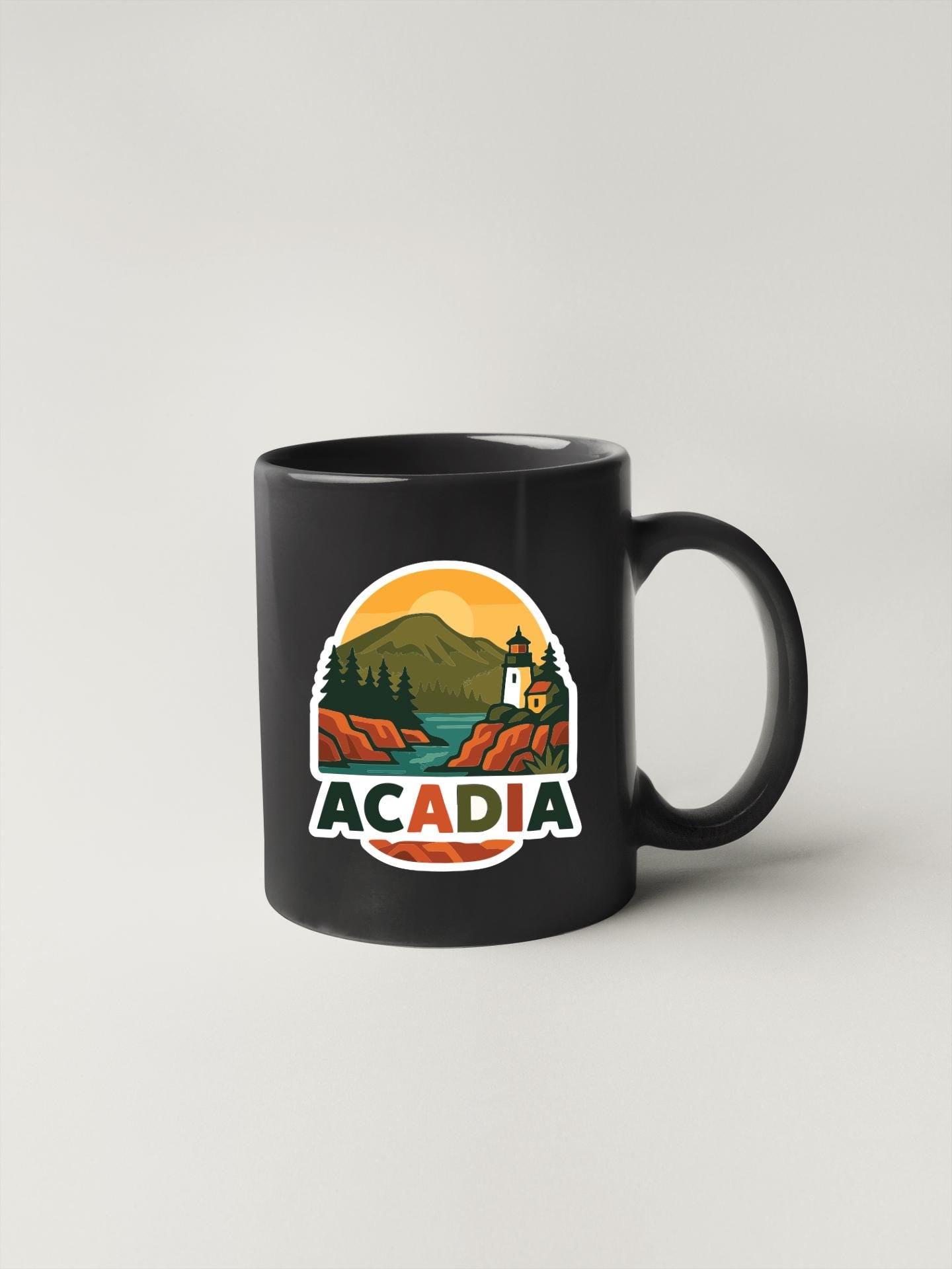 A black coffee mug with a graphic design depicting a scenic landscape with mountains, a lighthouse, and a body of water.