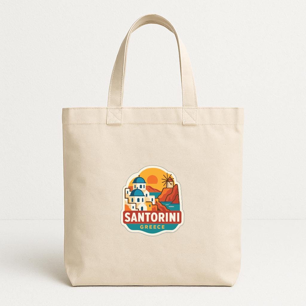 A beige tote bag with a graphic design featuring a scenic view of Santorini, Greece.
