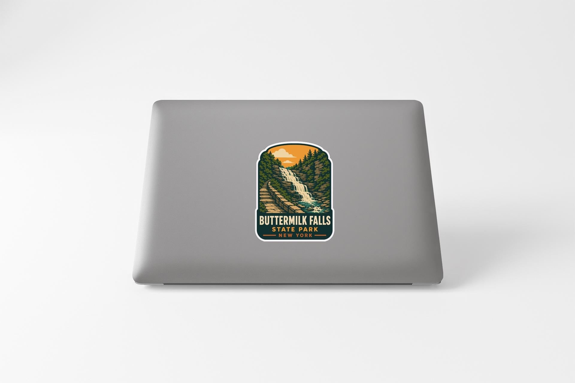 A sticker depicting Buttermilk Falls State Park on a laptop.