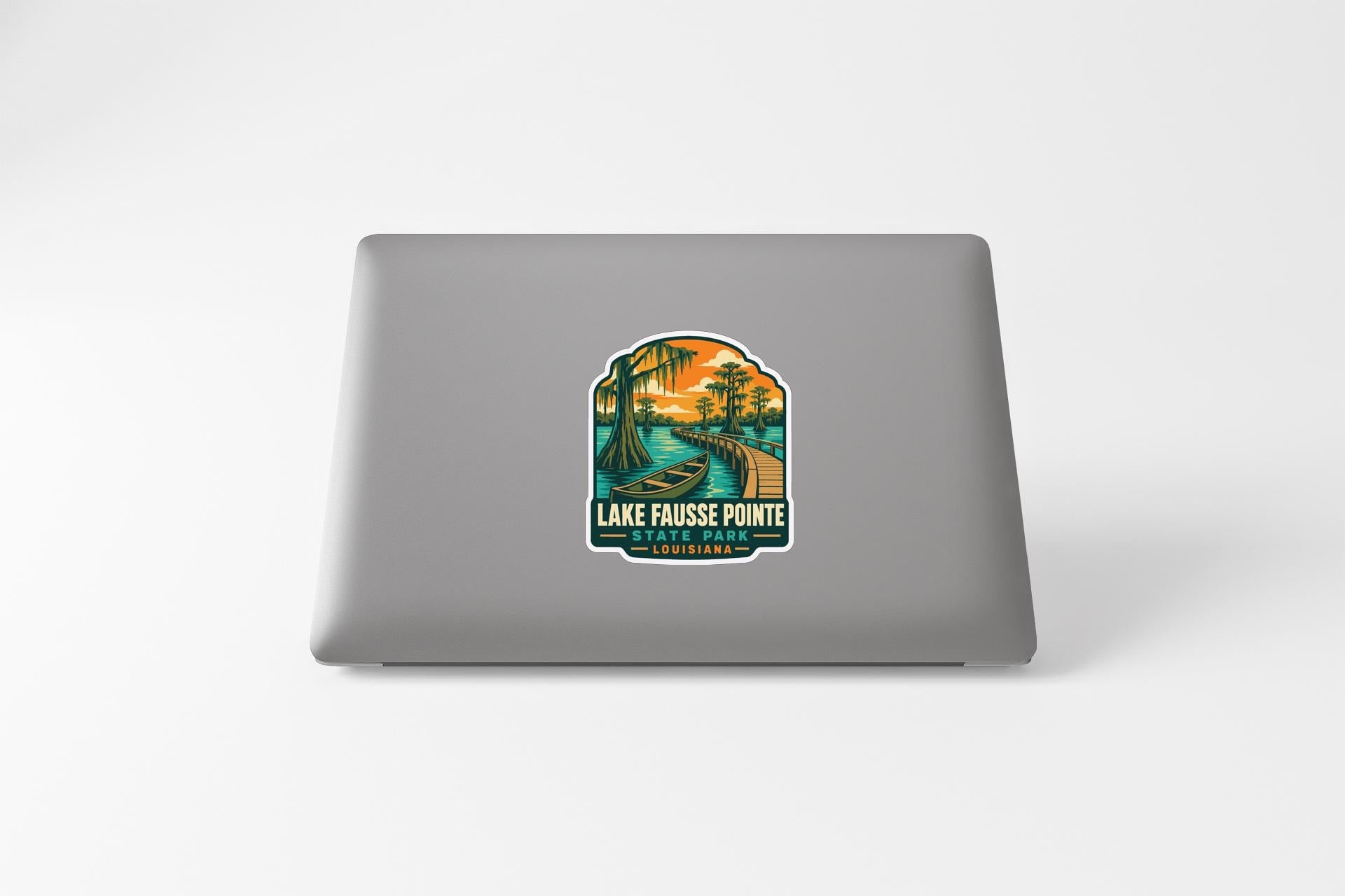 A sticker on the back of a laptop, depicting a scenic landscape with a river, palm trees, and a sunset.