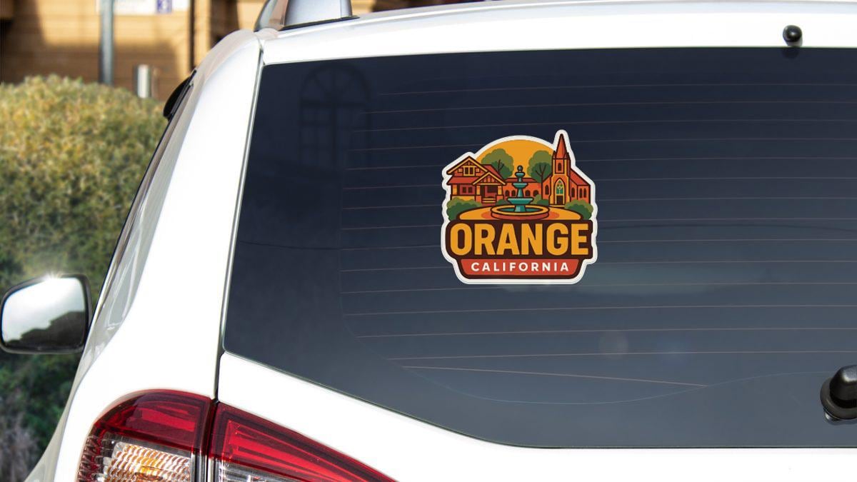 A sticker on the rear window of a white car that says "Orange California".