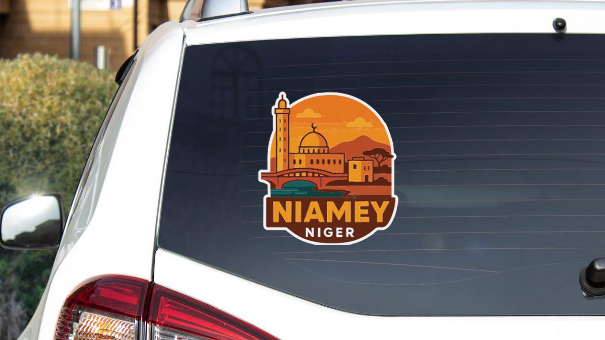 A sticker on the rear window of a car, depicting a cityscape with a prominent dome-shaped building and the text "NIAMEY NIGER".