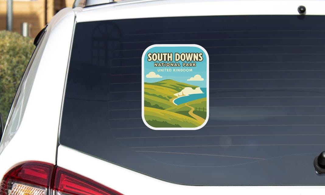 A sticker on the rear window of a car, depicting a scenic landscape with mountains, a river, and a blue sky with clouds.