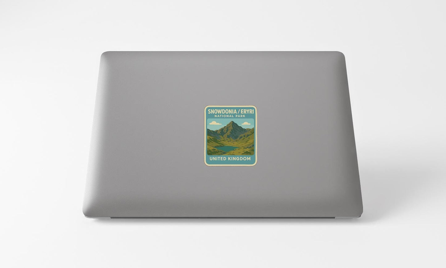 A sticker on the back of a laptop, depicting a mountain landscape with a lake.