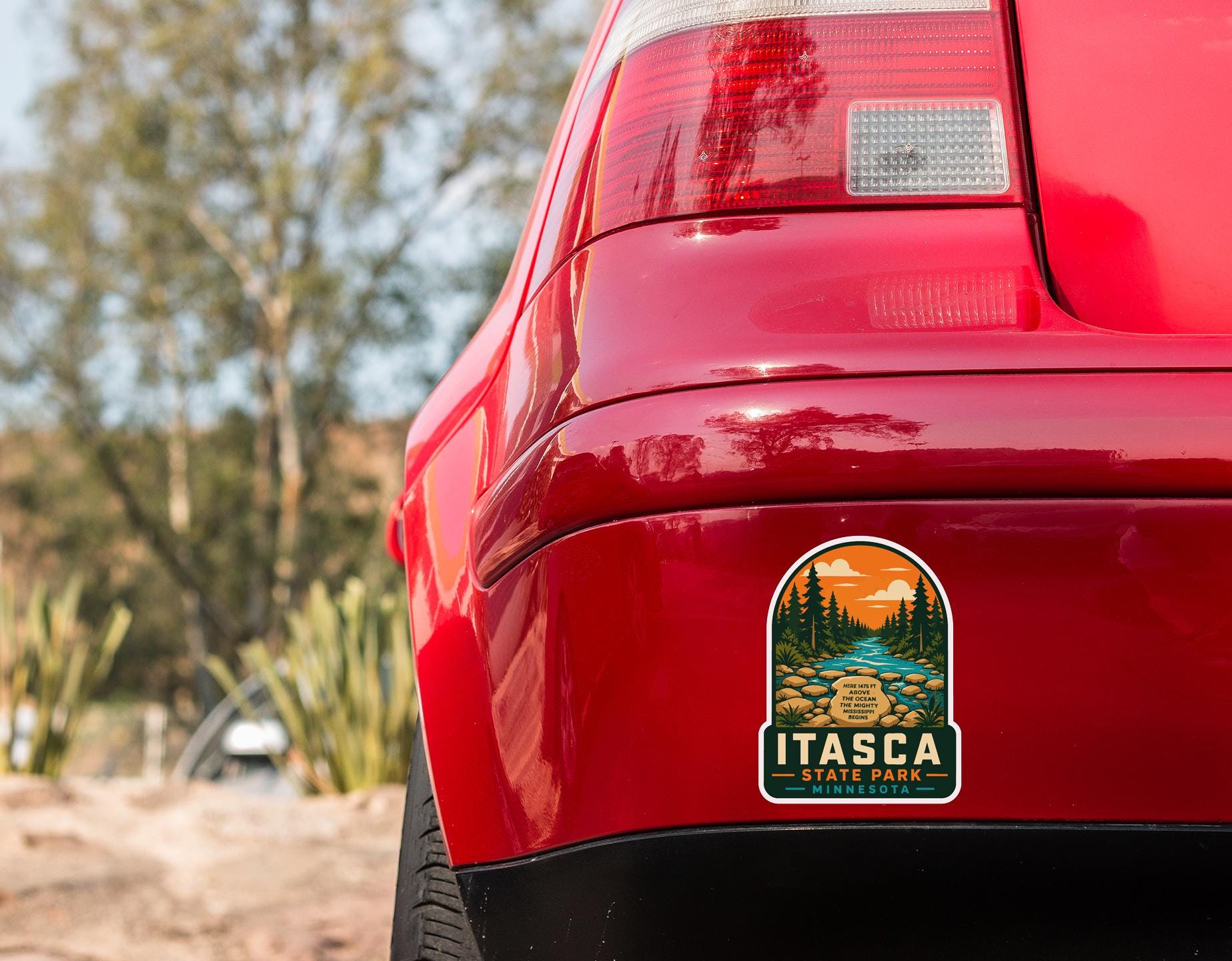 the rear end of a red car with a sticker on the trunk that says "ITASCA ITALES, MINNESOTA".