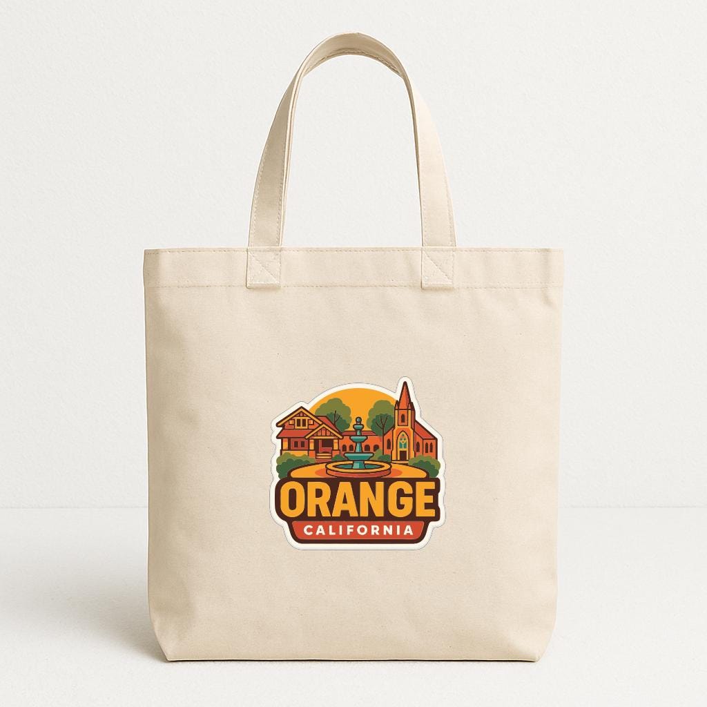 A beige tote bag with a printed design of a cityscape and the text "ORANGE CALIFORNIA" printed on it.