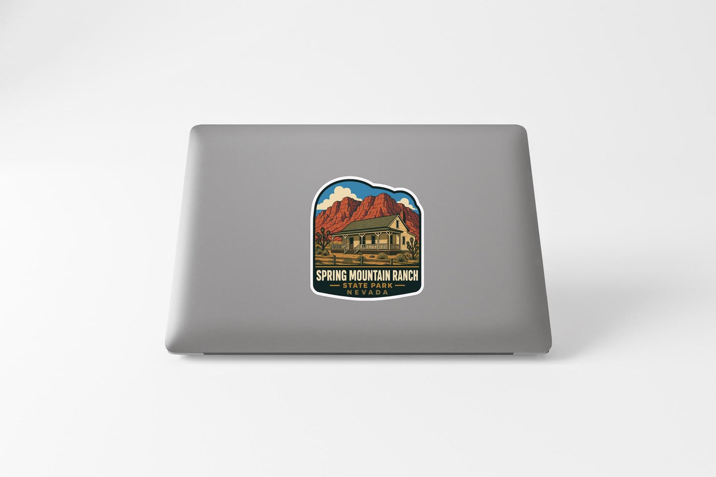 A sticker on the back of a laptop, depicting a scenic mountain landscape with a cabin in the background.