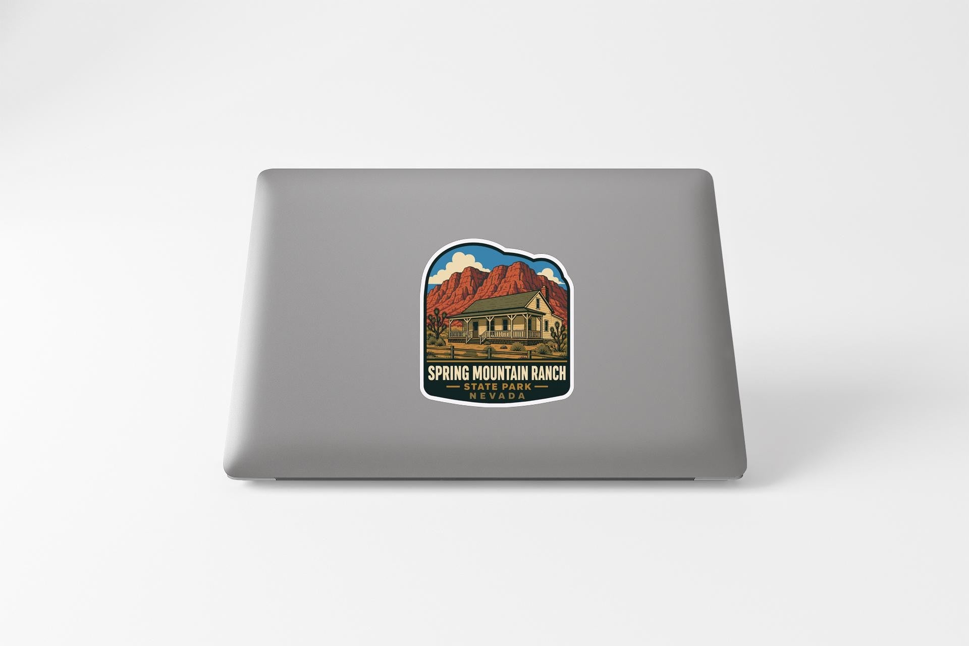 A sticker on the back of a laptop, depicting a scenic mountain landscape with a cabin in the background.