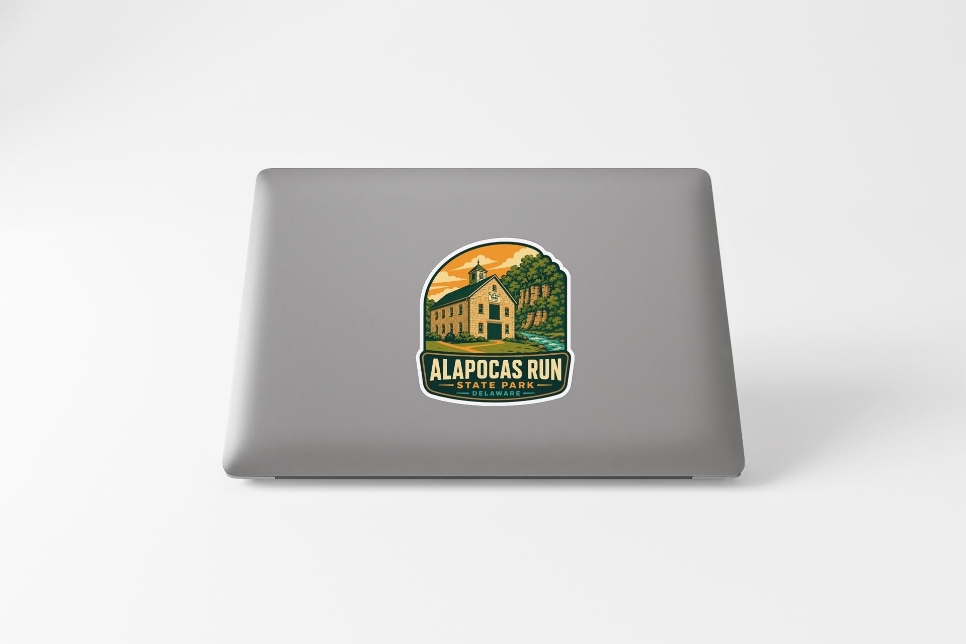 a sticker on a laptop that displays a scenic image of a building and a river, along with the text "ALAPOCAS RUN STATE PARK".