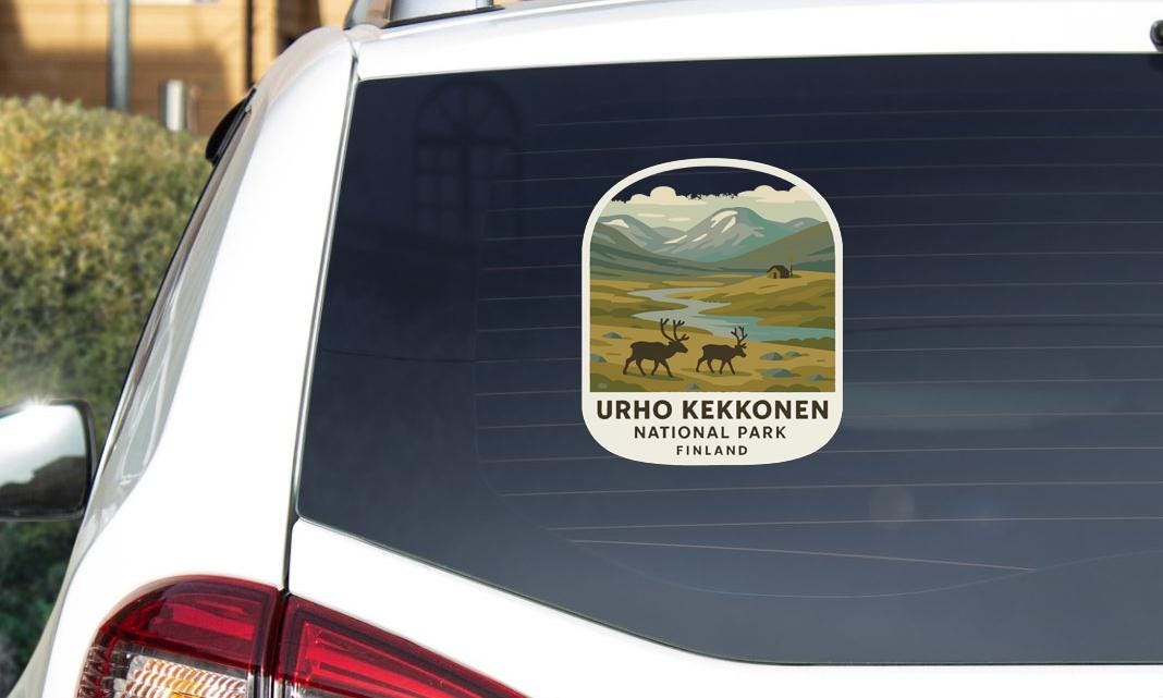 A sticker on the rear window of a car, depicting a scenic landscape with mountains, a river, and two reindeer.