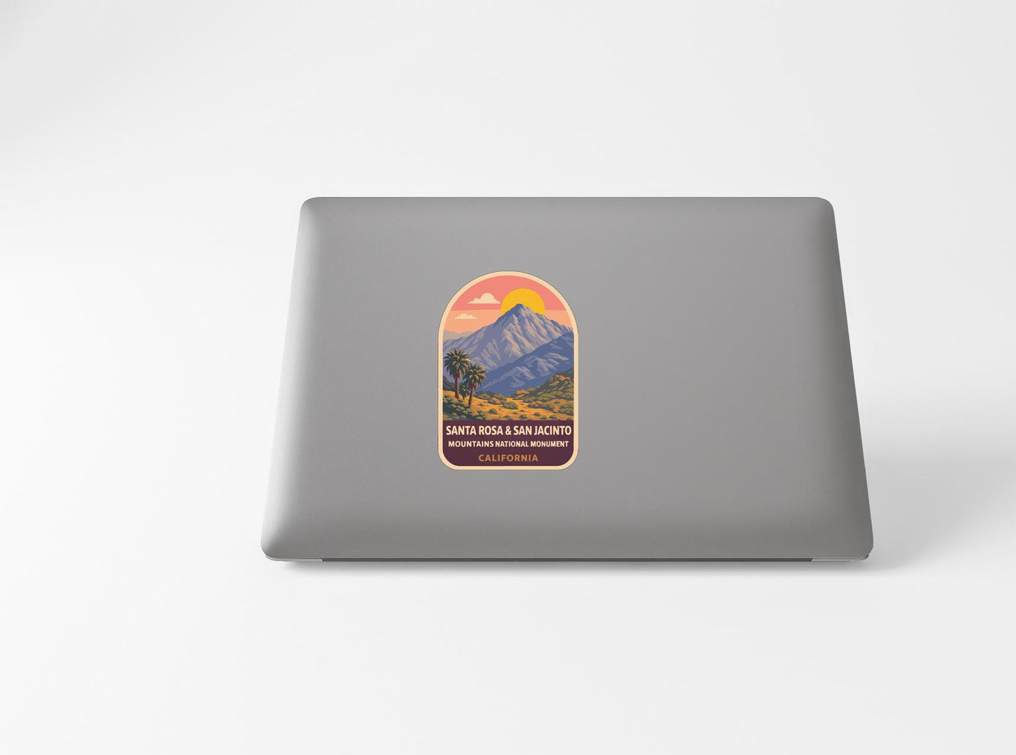 a sticker with a mountain landscape and a sunset on a laptop.