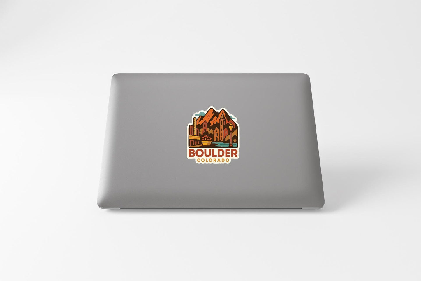 a sticker with a mountain landscape and the text "Boulder, Colorado" on the back of a laptop.