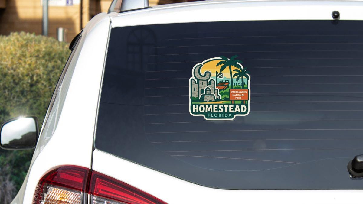 the rear window of a white car with a sticker on it.
